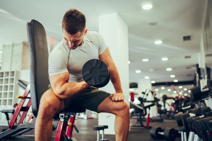 man doet concentratie curls in de sportschool