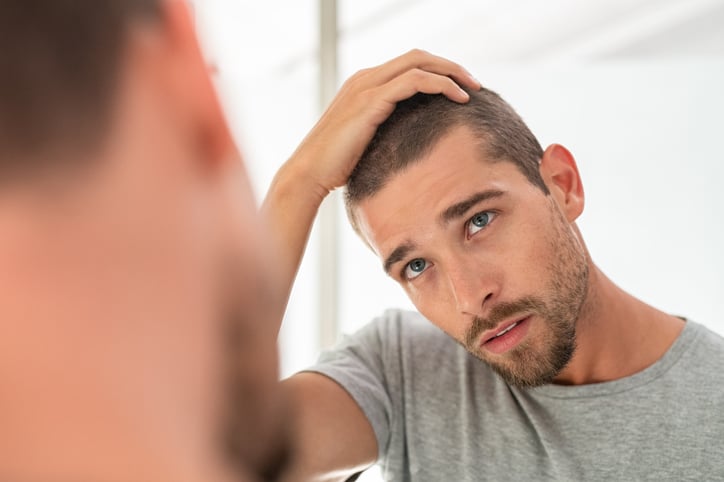 Man kijkt naar dunner wordend haar in spiegel