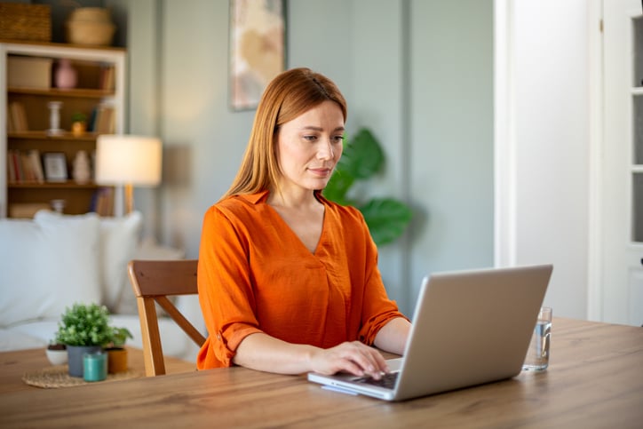 Vrouw zit geconcentreerd achter de laptop