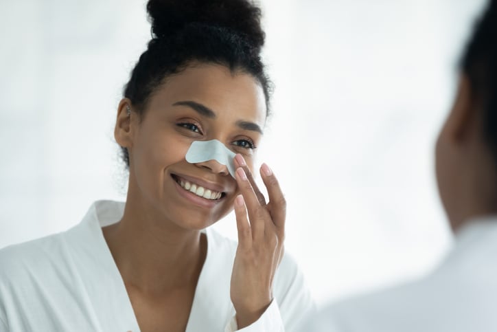 zwarte vrouw kijkt lachend in de spiegel met een nosestrip op haar neus