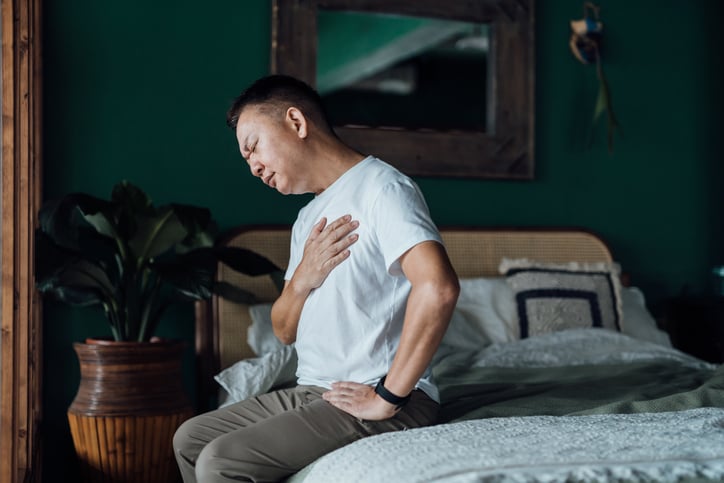 Persoon op bed voelt met hand op zijn borst
