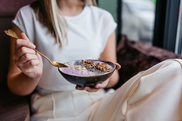 Vrouw eet smoothie bowl met noten en zaden