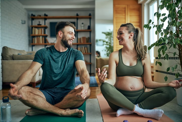 Man en zwangere vrouw doen samen yoga voor beweging