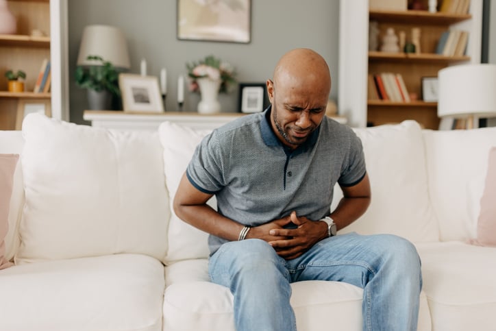 Man zit op de bank met buikpijn.