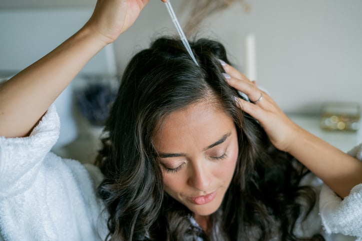 Vrouw brengt kokosolie serum op de hoofdhuid aan