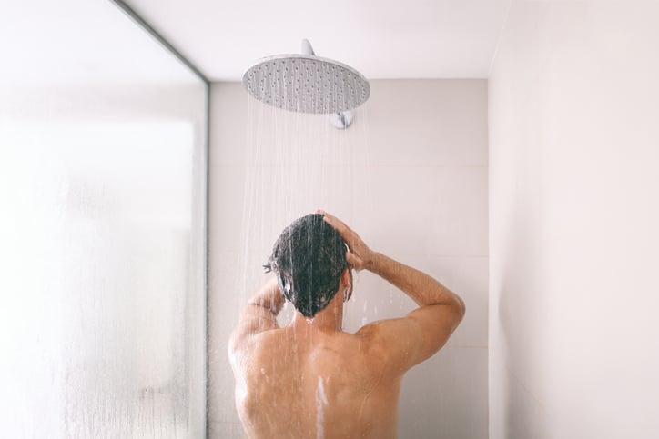Man spoelt met koel water onder de douch