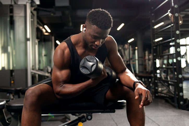 Man doet bicep curl met een dumbell in de sportschool