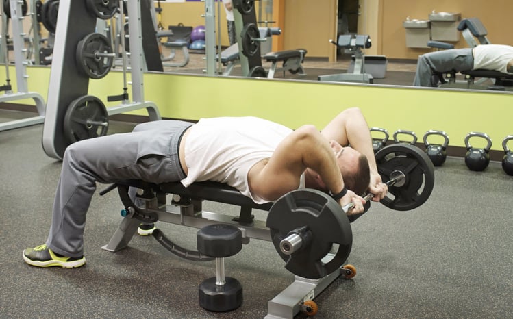 Man doet tricep skull crusher in de sportschool