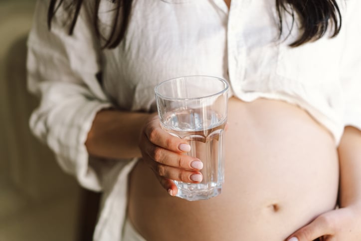 Zwangere vrouw houdt glas water vast