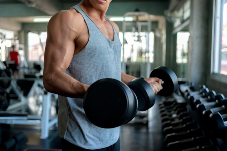 man doet bicep curl in sportschool