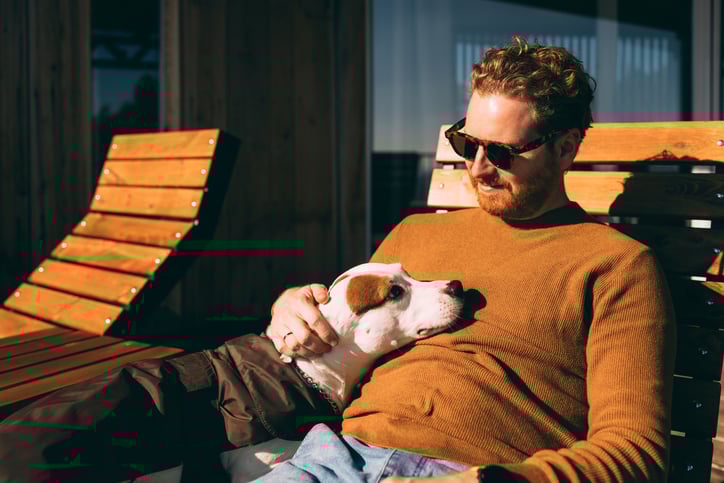 Man met bruine trui aan zit met hond op schoot