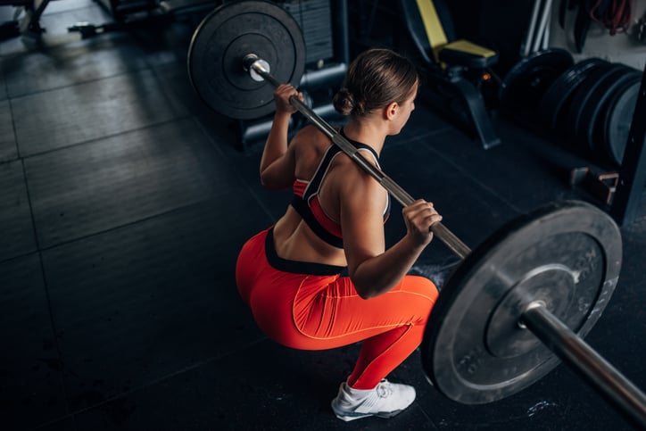Vrouw doet back squat in de sportschool