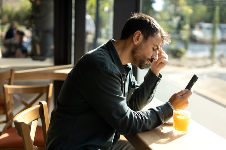 Man is vermoeid en zit kijkt naar mobiel