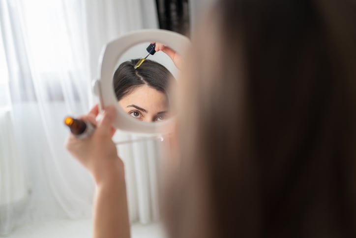 Vrouw doet haarserum op hoofd