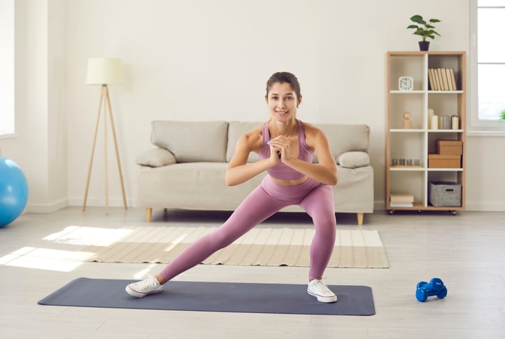 Vrouw doet lateral lunges in de woonkamer