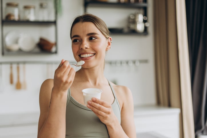 Lachende vrouw geniet van yoghurt