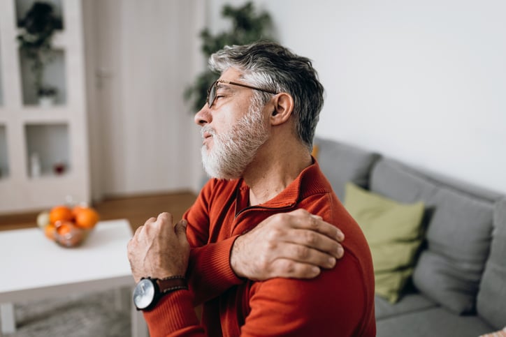 Man grijpt naar schouder