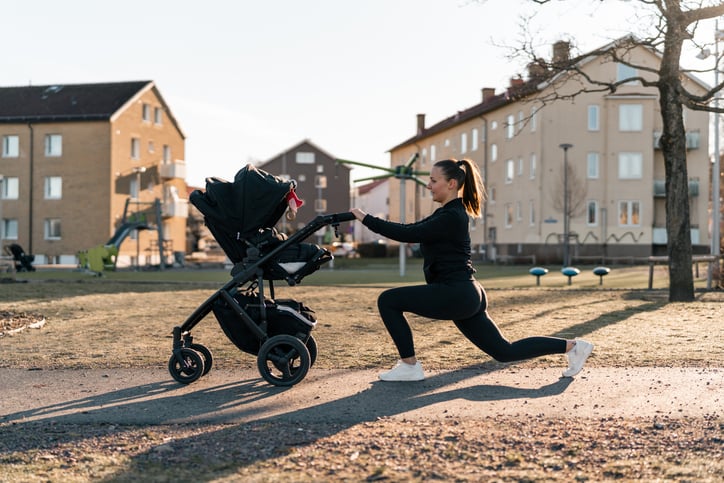 Vrouw doet lunges in de speeltuin met kinderwagen