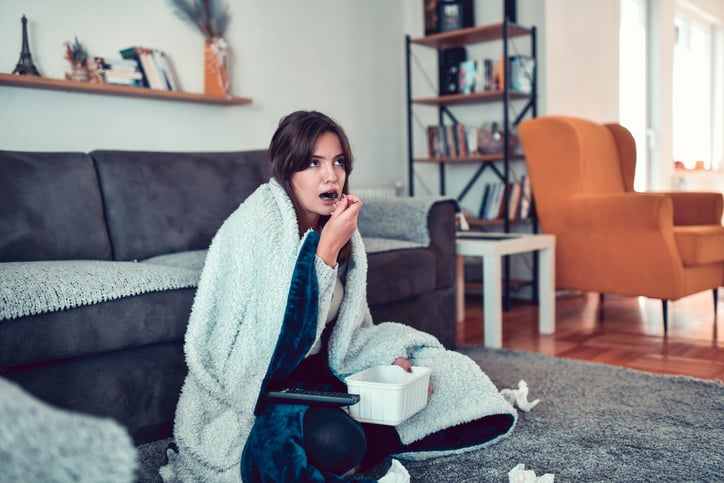 Vrouw eet uit emotie zittend op de grond