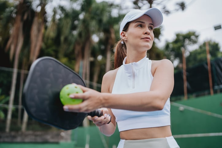 Vrouw is aan het sporten met een racket en bal in de hand